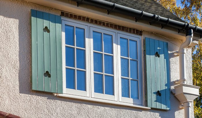 White uPVC flush sash windows with green shutters