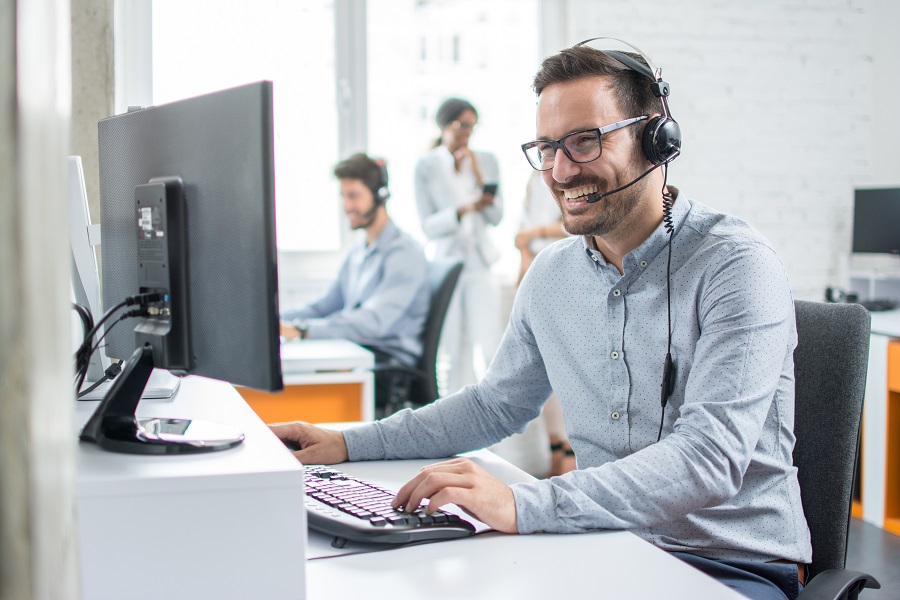 Smiling customer support operator with hands-free headset working.